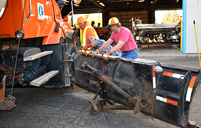 Photo of Joann Schuler, Dan Huycke and Henry Erickson working on snowplow.